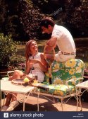 1970s-relaxing-couple-sitting-on-patio-furniture-with-drinks-both-G6A71F.jpg