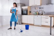 92351413-happy-woman-cleaning-floor-with-mop-in-kitchen-at-home.jpg