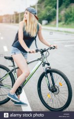 girl-on-a-bicycle-spring-morning-on-road-KPNNP2.jpg