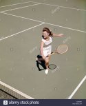 1960-1960s-retro-smiling-woman-playing-tennis-swinging-racket-to-hit-CMRP9R.jpg